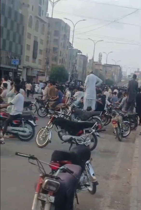Crowd of motorcyclists performing stunts and illegal racing on Ghizri Bridge in Karachi causing traffic disruption and safety concerns.