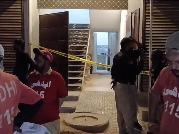 Police and crime scene investigators at the site where five family members were found dead in Karachi